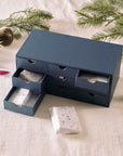 Close-up of the Tom’s Studio Advent Calendar drawers partially open, revealing wrapped gifts inside with gold festive illustrations.
