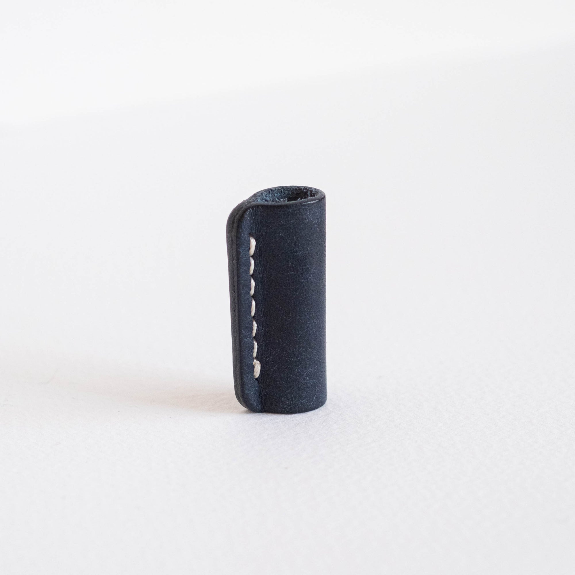 Midnight leather Lumos grip and rollstop standing upright on a white background, showing hand-stitched detail.