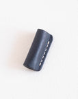Midnight leather grip and rollstop for the Lumos pen, lying flat with visible white stitching on a clean white surface.
