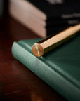 Close-up of the end of the Brass Wren lid, highlighting its solid octagonal brass lid on a green notebook.