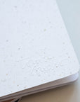 Detail of embossed logo on Tom's Studio x Coffeenotes A6 Notebook in 'Grounds' (white), made from recycled coffee cups and eco-friendly materials.