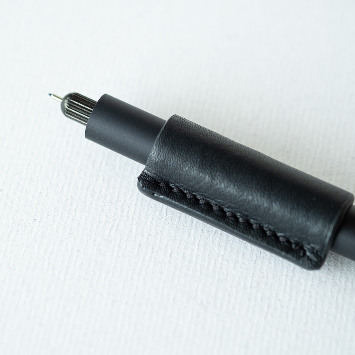 Handmade by Edward De Lacy, a leather pen grip and rollstop for the Lumos refillable pen – shown in black leather on the black Lumos