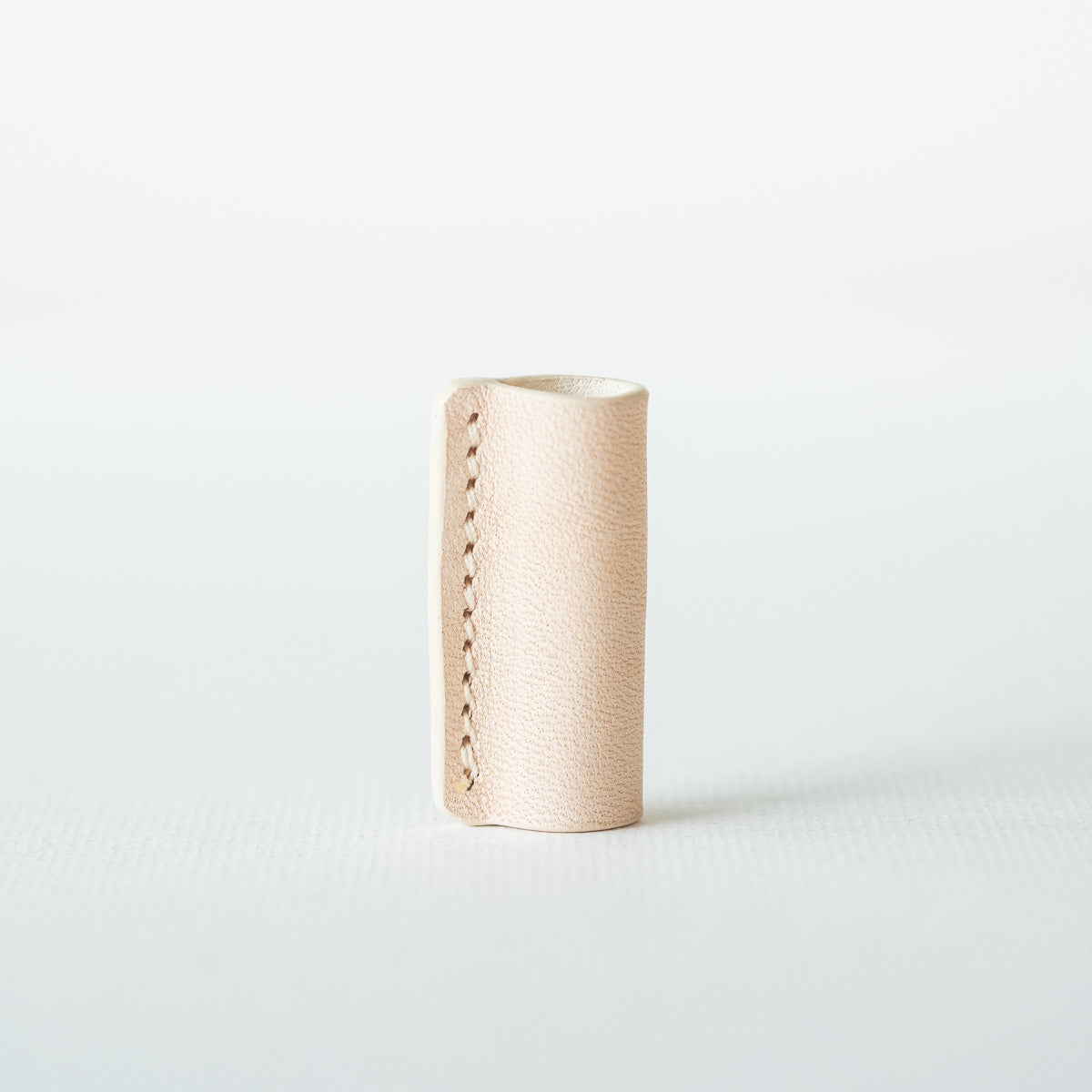 Handmade by Edward De Lacy, a leather pen grip and rollstop for the Lumos refillable pen – shown in natural leather