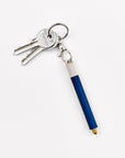 A close-up of a Lumos Loop Lid attached to a Midnight Lumos Mini pen, clipped onto a keyring. The cap is slightly open, showing the interchangeable writing tip.