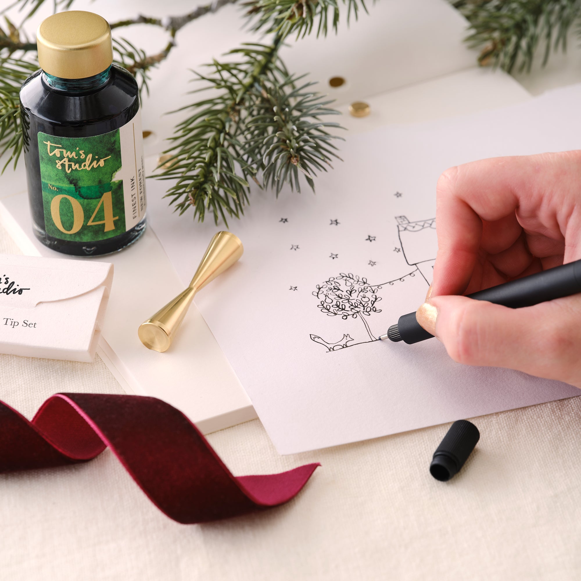 Contents of the Lumos Pro Duo Gift Set including: Lumos Pro Duo refillable pen in Black, 50ml bottle of Fountain Pen Ink in New Forest, the Studio Pad and Butterfly Brass Pen Rest