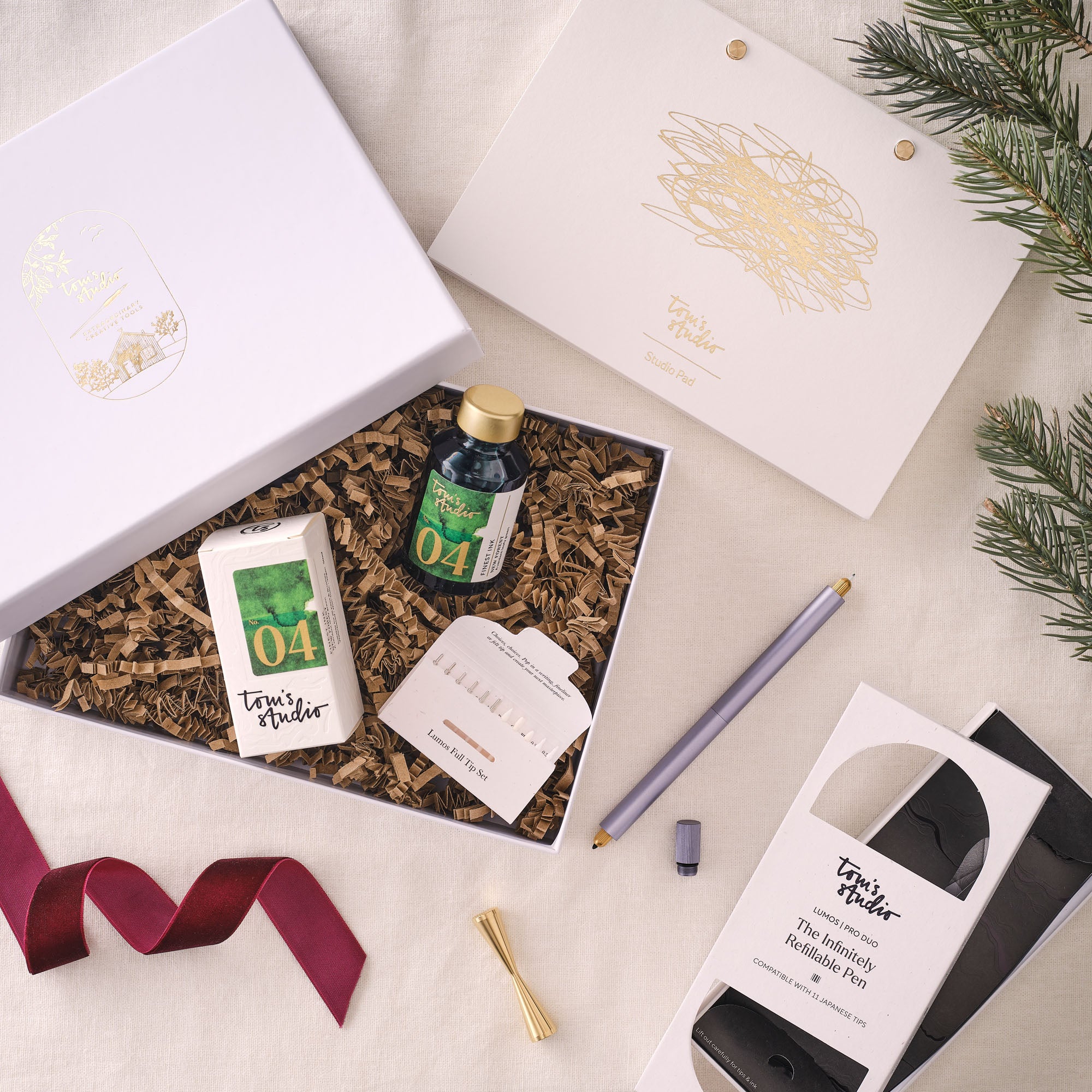 Contents of the Lumos Pro Duo Gift Set including: Lumos Pro Duo refillable pen in Lilac, 50ml bottle of Fountain Pen Ink in New Forest, the Studio Pad and Butterfly Brass Pen Rest