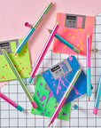 Flat lay of Lumos Splash pens in neon Appletini, Blue Raspberry, and Bubblegum colourways, styled with colourful floppy disks on a grid background.