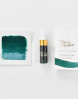 A mini ink sample bottle of Mallard green fountain pen ink by Tom’s Studio, displayed alongside a swatch of the ink on textured paper and its matching packaging. The bottle is small, with a gold cap and a white pipette dropper, and features 'Tom’s Studio' in gold lettering. The ink swatch shows a rich, shimmering hue with a gradient from deep to lighter tones. The packaging, a small white card, has 'Tom’s Studio' embossed in gold at the top, with a brushstroke of the ink colour at the bottom.