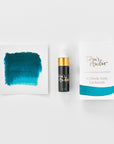 A mini ink sample bottle of Neptune blue fountain pen ink by Tom’s Studio, displayed alongside a swatch of the ink on textured paper and its matching packaging. The bottle is small, with a gold cap and a white pipette dropper, and features 'Tom’s Studio' in gold lettering. The ink swatch shows a rich, shimmering hue with a gradient from deep to lighter tones. The packaging, a small white card, has 'Tom’s Studio' embossed in gold at the top, with a brushstroke of the ink colour at the bottom.
