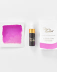 A mini ink sample bottle of Cherry Bomb pink shimmer fountain pen ink by Tom’s Studio, displayed alongside a swatch of the ink on textured paper and its matching packaging. The bottle is small, with a gold cap and a white pipette dropper, and features 'Tom’s Studio' in gold lettering. The ink swatch shows a rich, shimmering hue with a gradient from deep to lighter tones. The packaging, a small white card, has 'Tom’s Studio' embossed in gold at the top, with a brushstroke of the ink colour at the bottom.