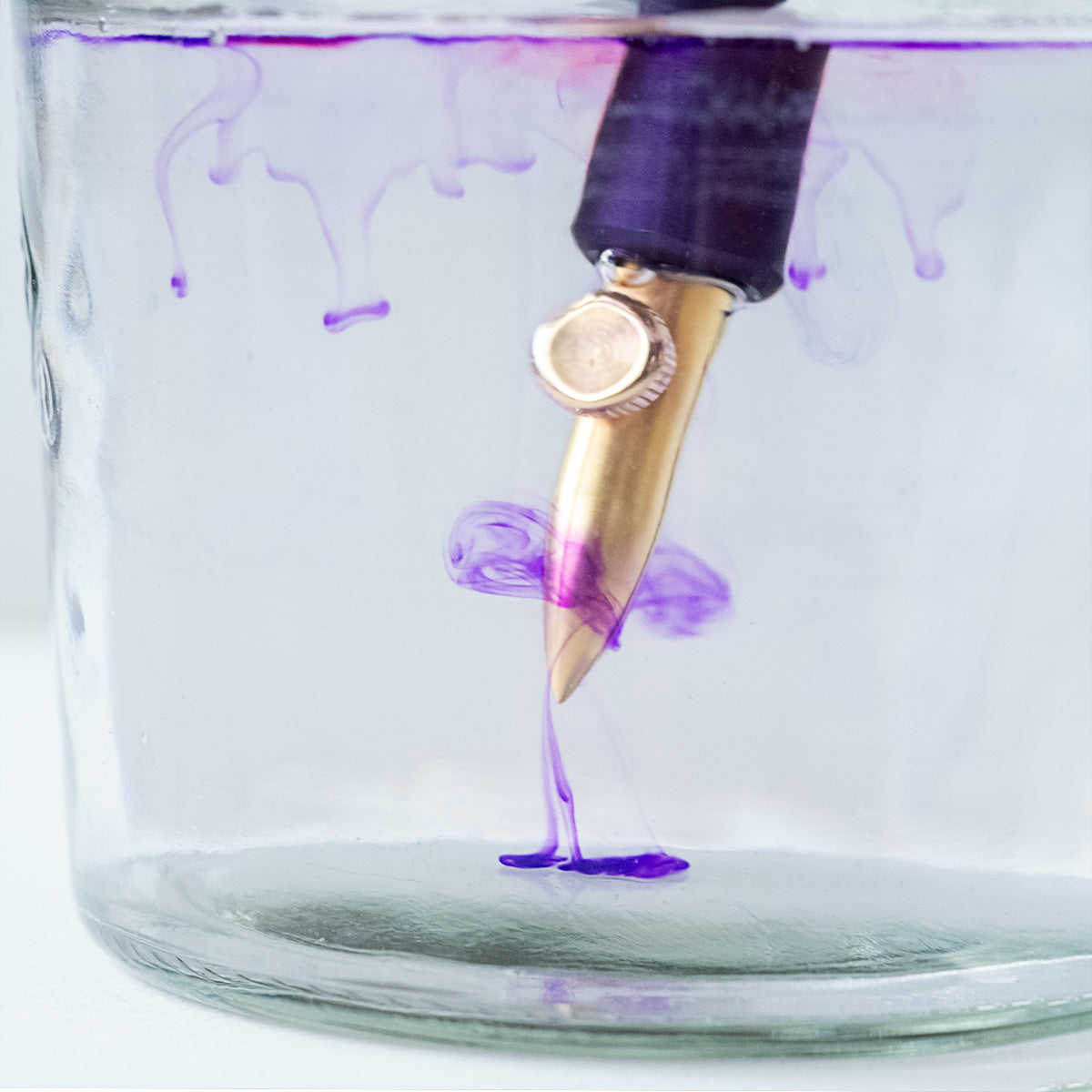 The One-Dip-Nib in Brass, shown being rinsed of ink in a beaker of water