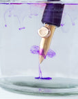 The One-Dip-Nib in Brass, shown being rinsed of ink in a beaker of water