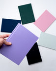 A collection of vibrant Semikolon A5 notebooks in various colours, with premium linen bound covers, in a spiral arrangement.