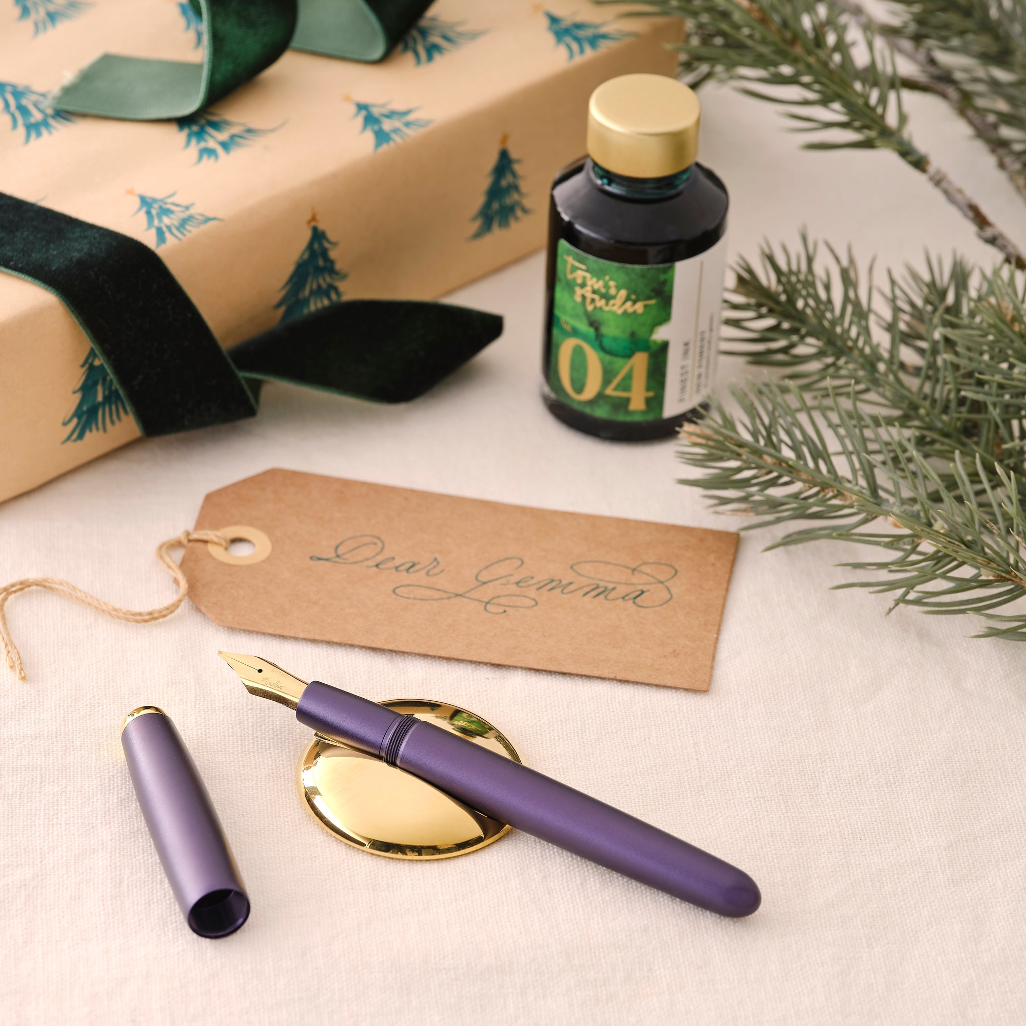 Contents of the Studio Fountain Pen Gift Set including Studio Fountain pen in Iris with Medium Gold nib, New Forest Green Fountain Pen Ink and Solid Brass Pen Rest.