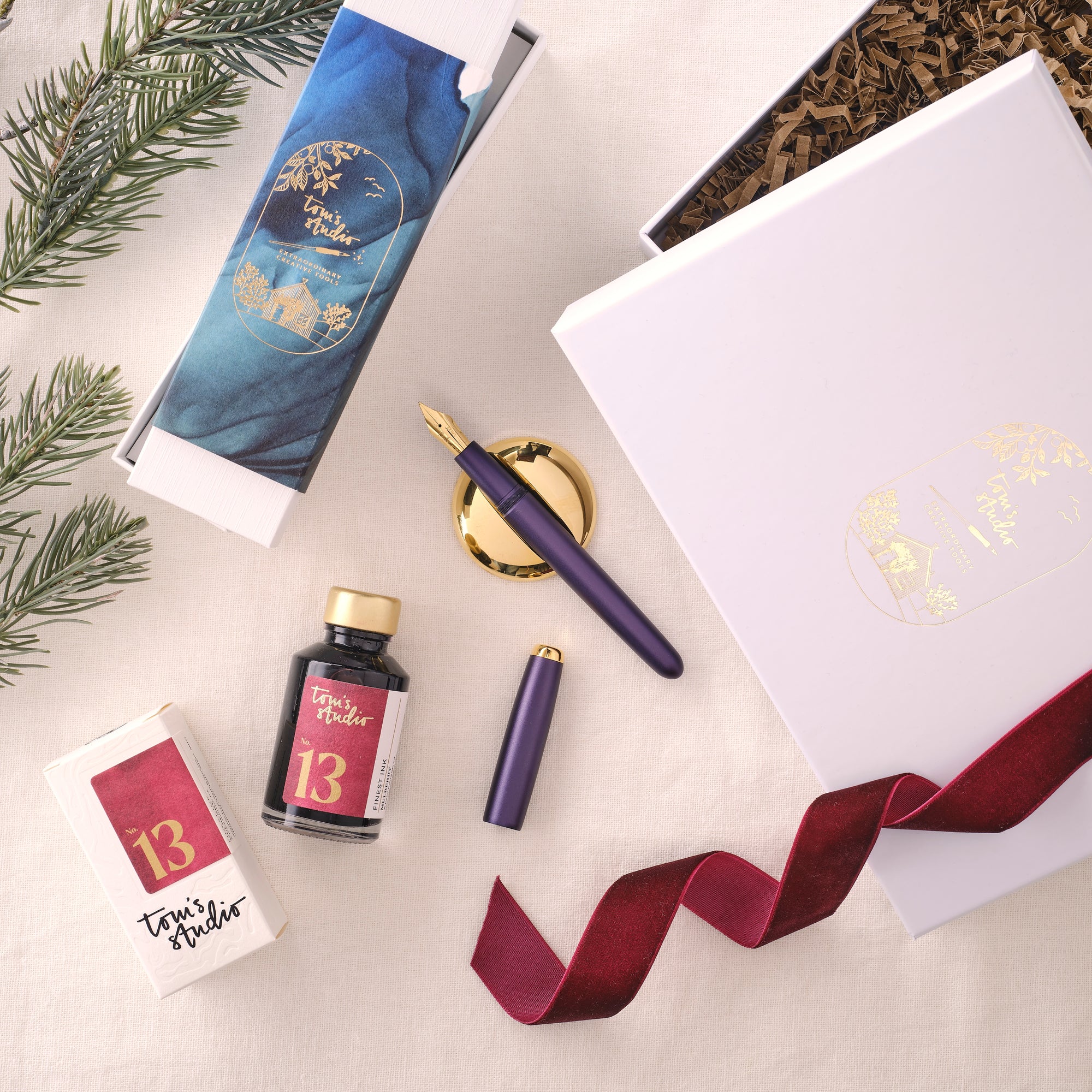 Contents of the Studio Fountain Pen Gift Set including Studio Fountain pen in Iris with Medium Gold nib, Mulberry Fountain Pen Ink and Solid Brass Pen Rest.