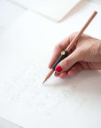 The Poise Pencil Grip Extender in Black. Shown in use preparing a calligraphy piece.