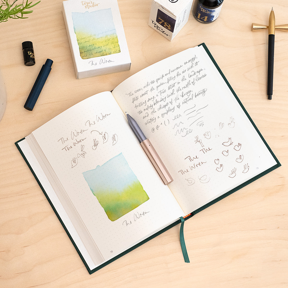 The Wren refillable everyday writing pen in Blush (lid) and Lilac (body) shown on an open notebook filled with writing and illustrations