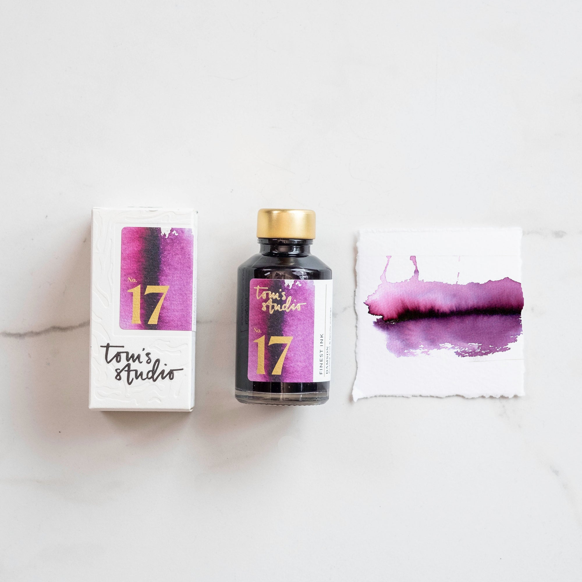 Tom's Studio Damson Fountain Pen Ink with two pens with inky goodness on paper with an ink swatch demonstrating the colour