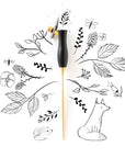 The Bloom calligraphy pen with oblique nib setting in Black on a background of illustrations in ink