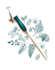 The Bloom calligraphy pen with oblique nib setting in Ivy on a background of illustrations in ink