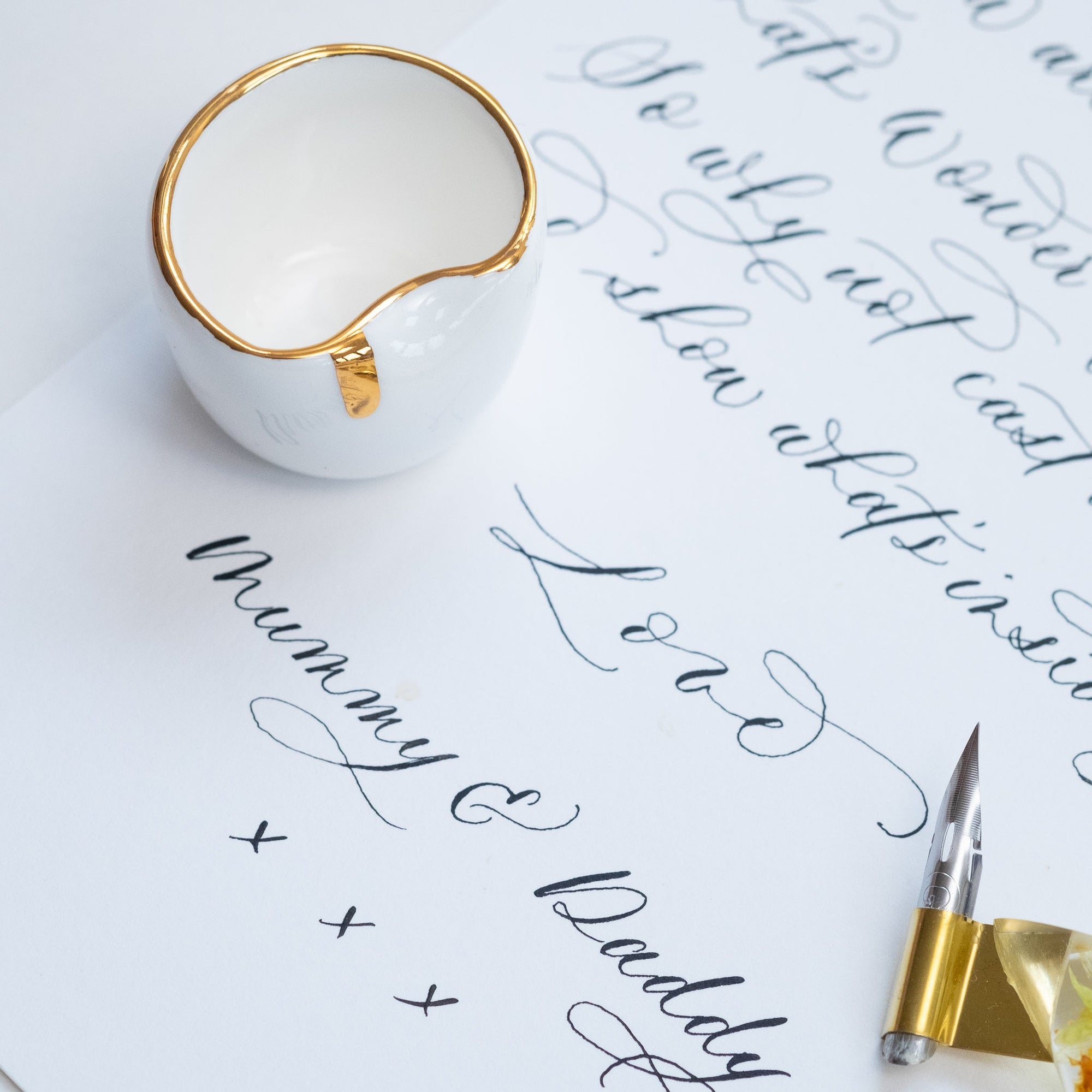 a fine bone china ink well on a sheet of paper with modern calligraphy written on it