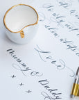 a fine bone china ink well on a sheet of paper with modern calligraphy written on it