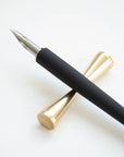 The Original Flourish Straight Calligraphy Pen in Black shown on the Butterfly Brass Pen Rest