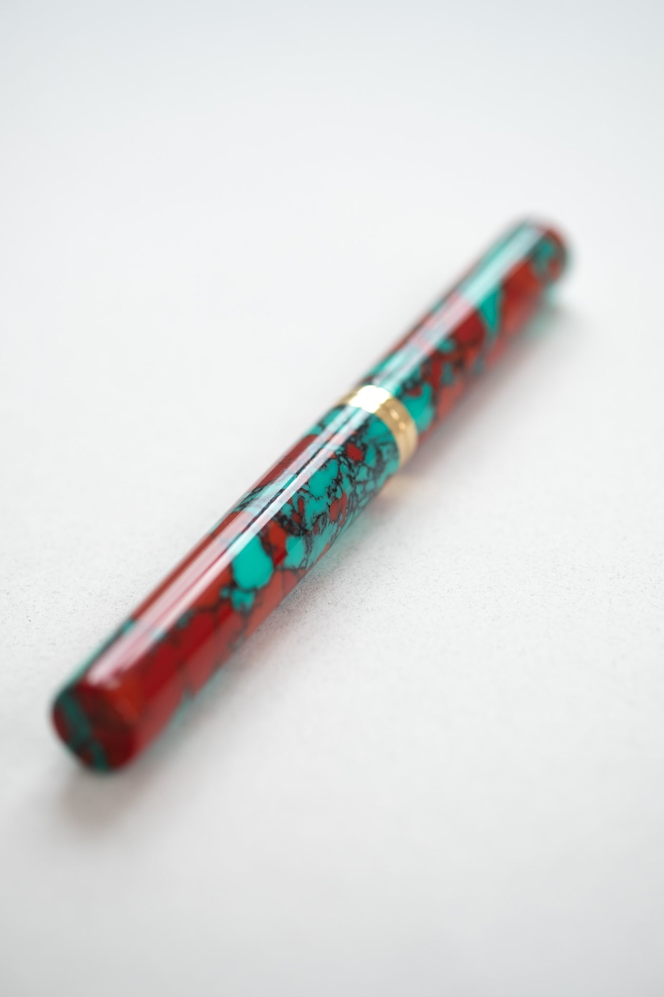 A close up of the red jasper Studio pen on a white desk with a flexible fountain pen nib