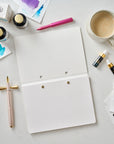 The Studio Pad in White – a refillable, customisable notebook and organiser laid open on a desk setup