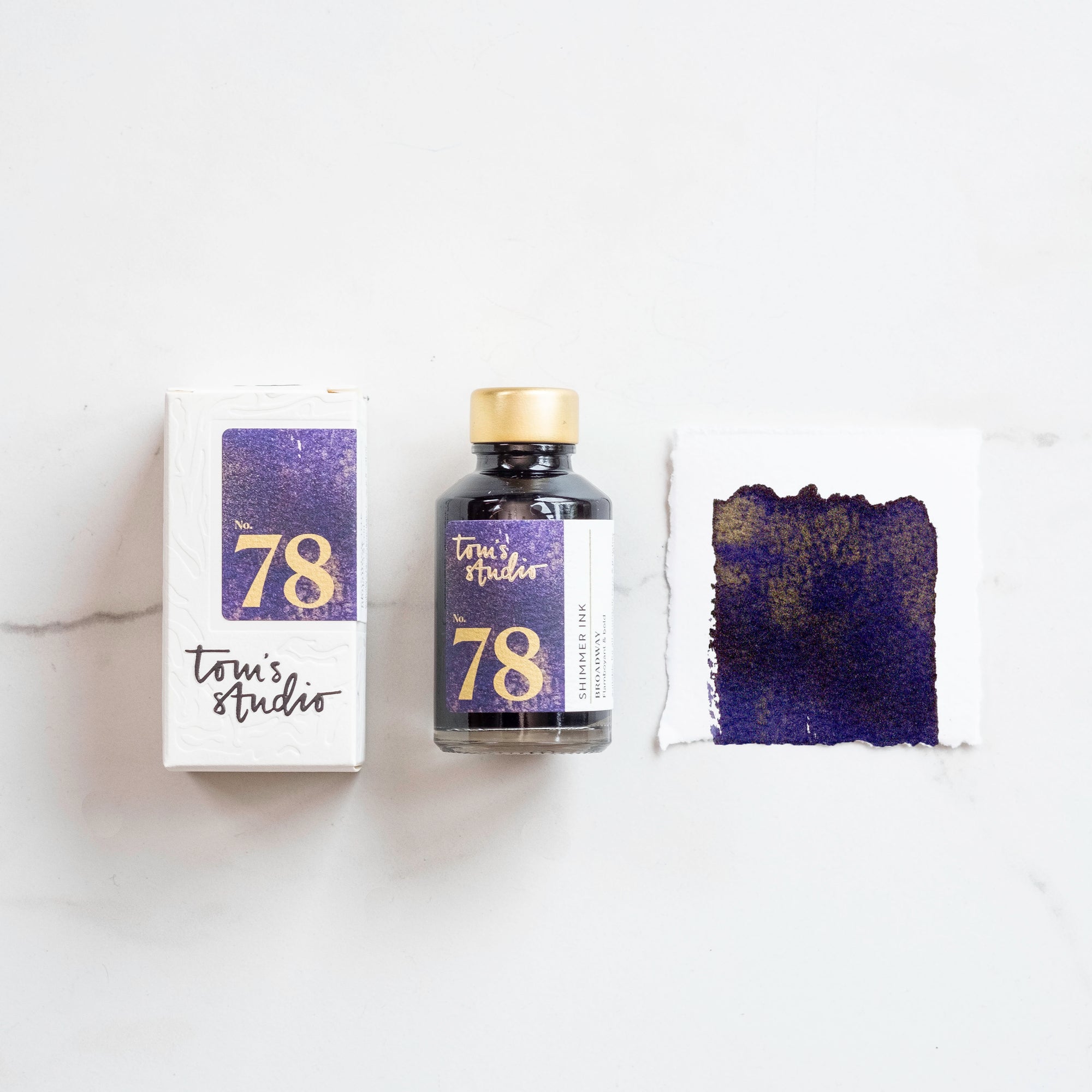 Tom's Studio Broadway Shimmer Fountain Pen Ink with two pens with inky goodness on paper with an ink swatch demonstrating the colour