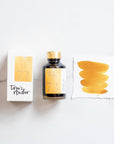 Tom's Studio Golden Lustre Shimmer Fountain Pen Ink with two pens with inky goodness on paper with an ink swatch demonstrating the colour