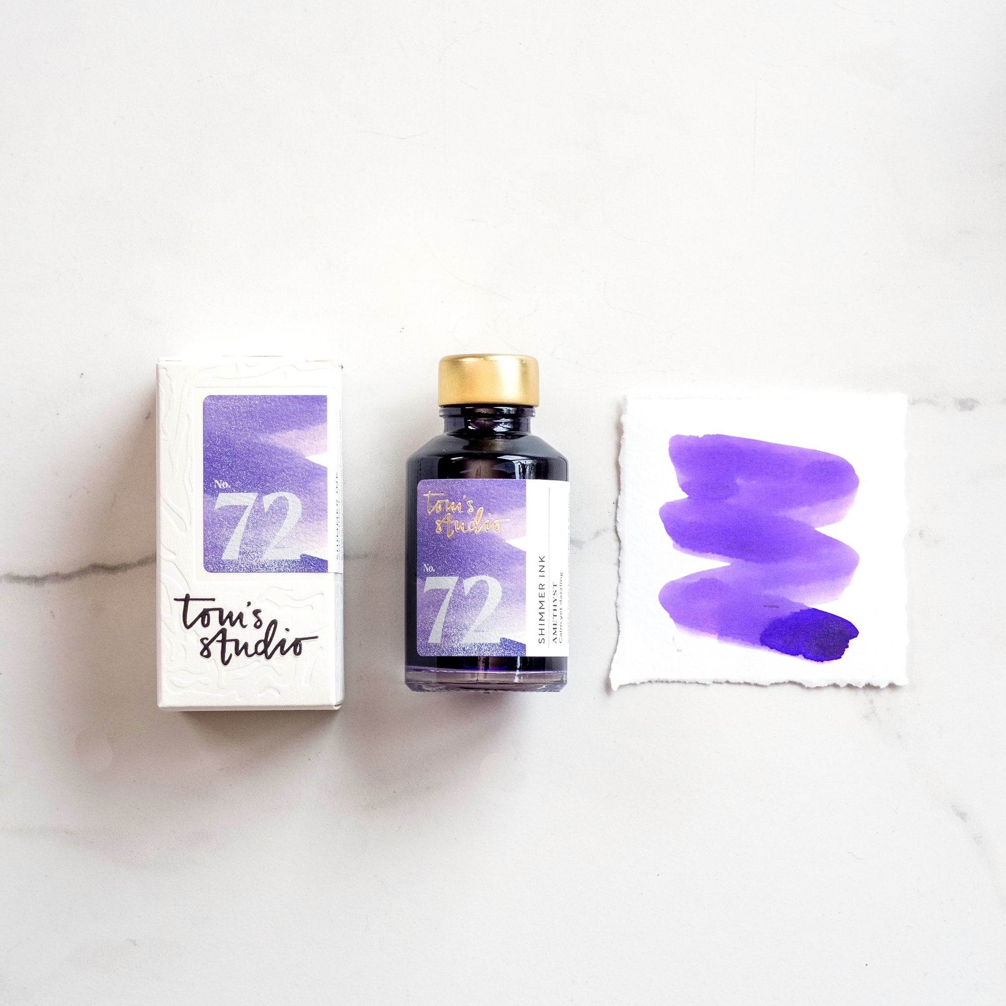 Tom's Studio Amethyst Shimmer Fountain Pen Ink with two pens with inky goodness on paper with an ink swatch demonstrating the colour