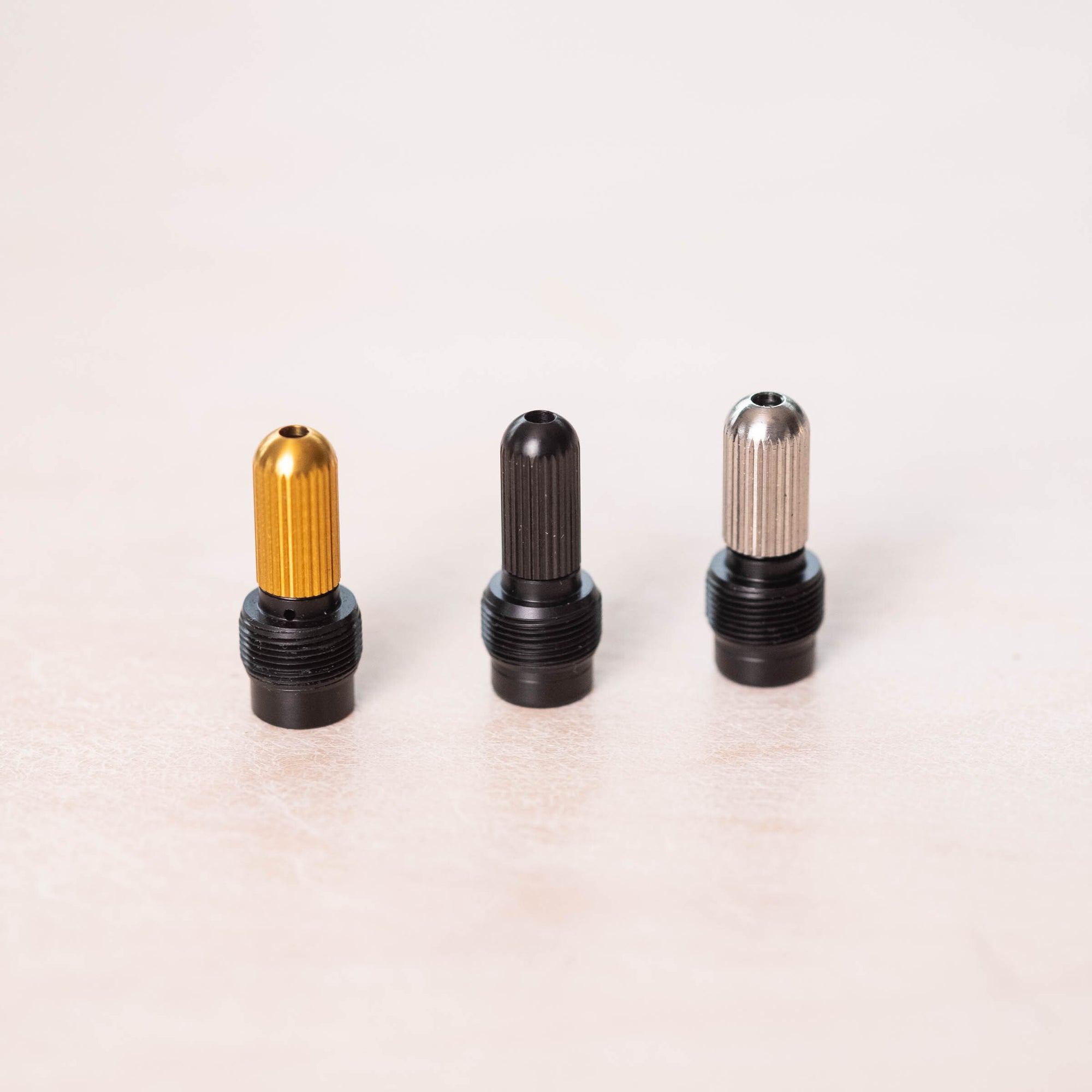 A group shot of the silver, black and gold tip holders displayed on a plain light background.