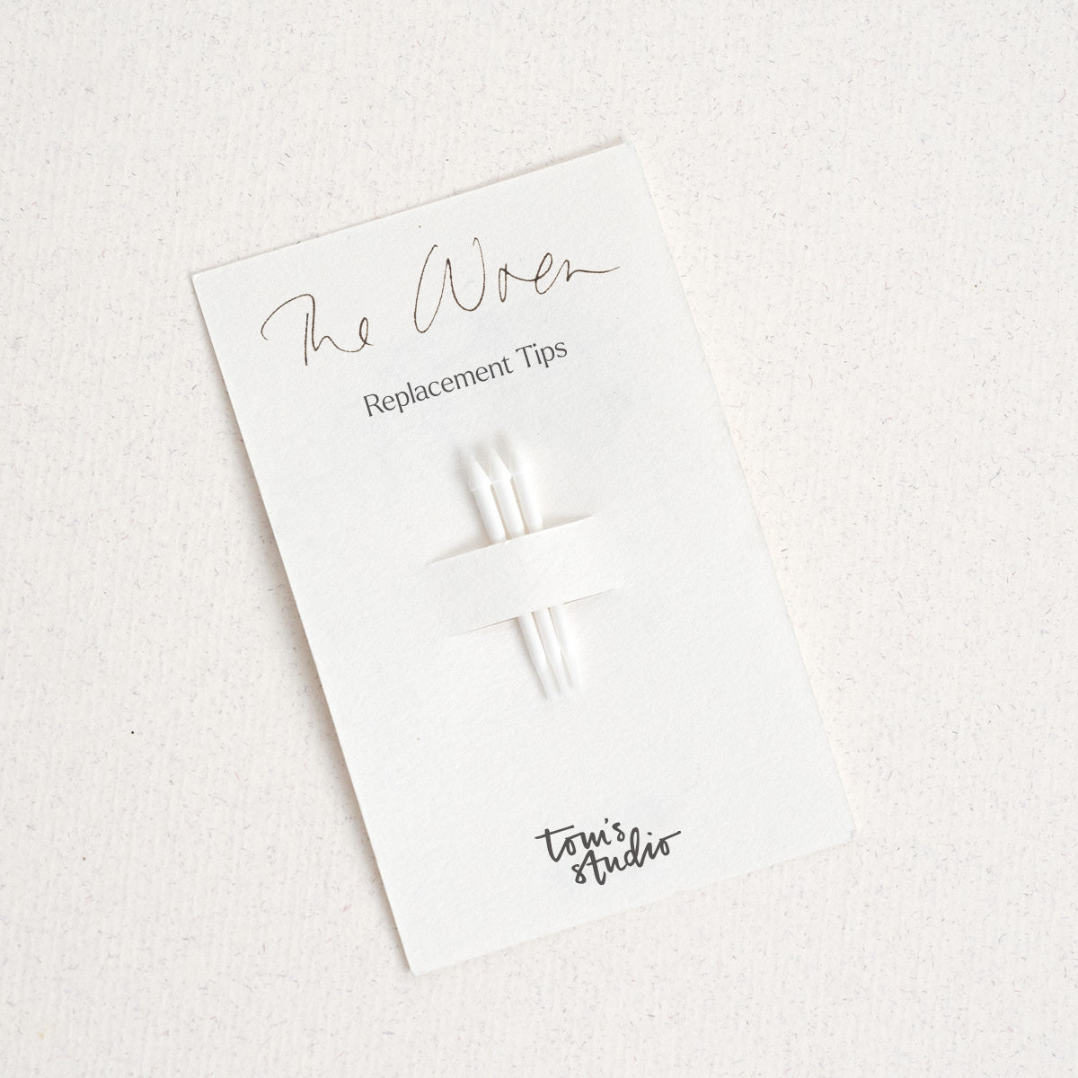 A packaging card for Wren replacement tips displayed on a light wooden surface. The card features a minimalist design with the text 'The Wren Replacement Tips' printed in black at the top. A small set of replacement tips is attached to the card, accompanied by a black Tom's Studio logo.