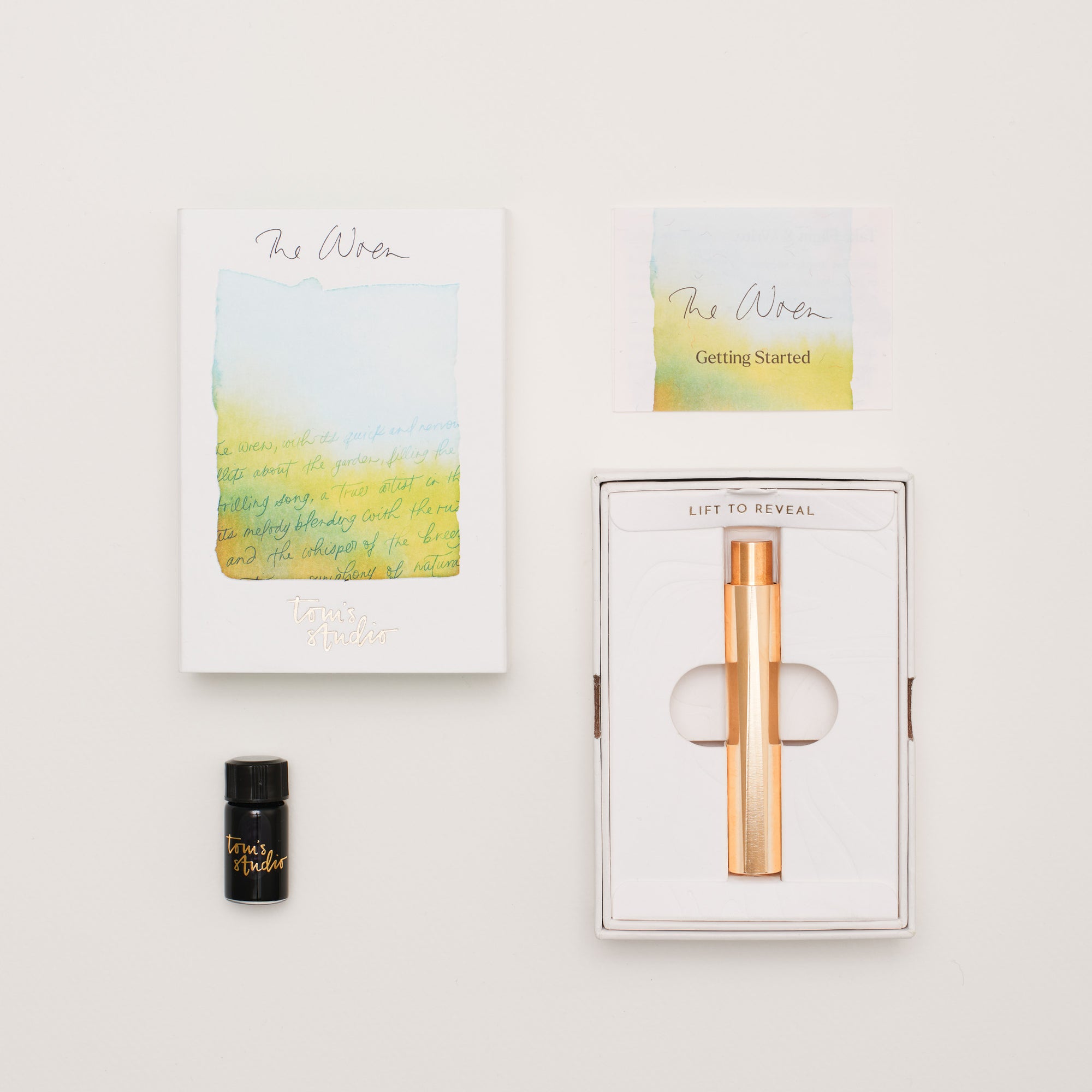 Brass Wren in its box, a small ink bottle, and a getting started guide, on a light background.