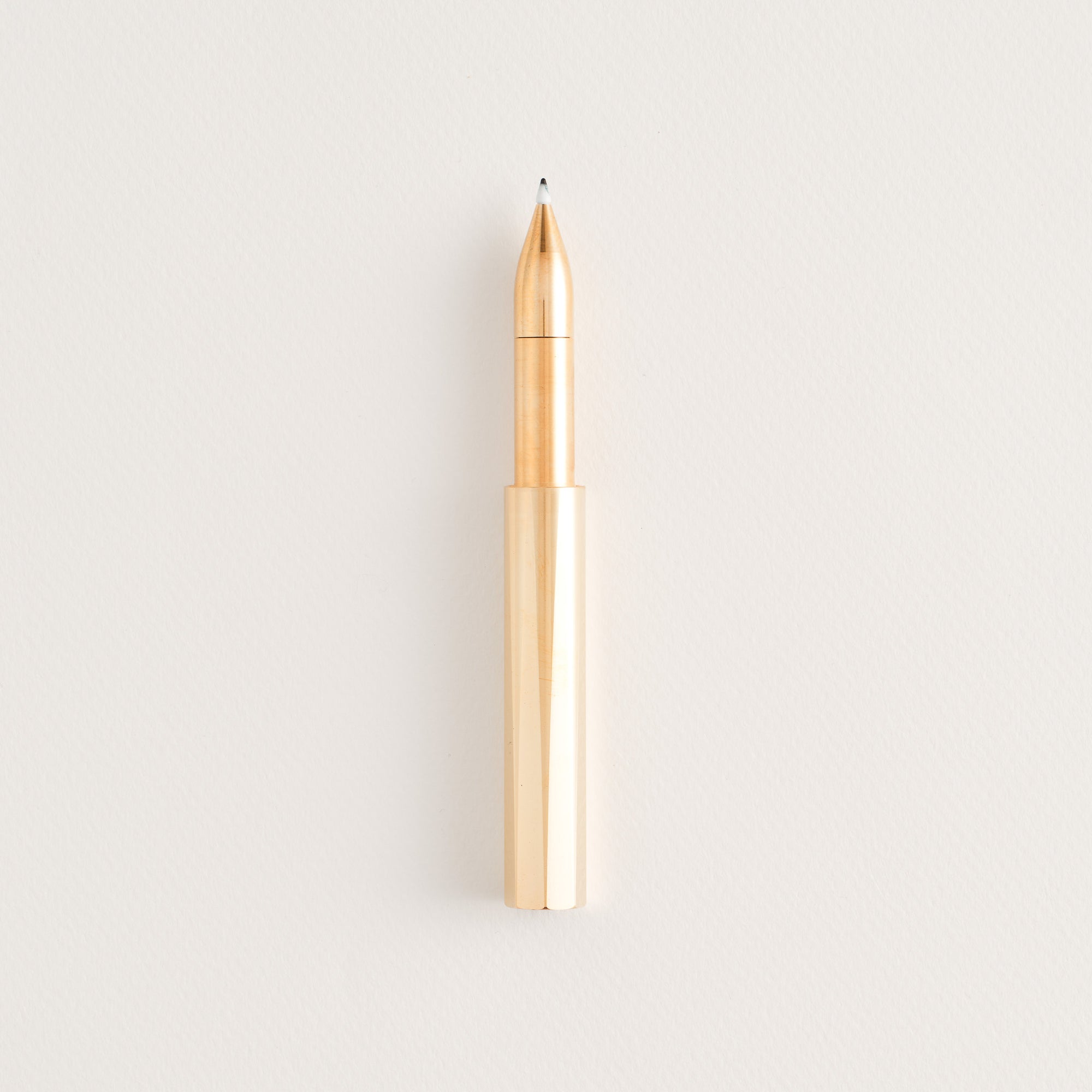 Brass Wren pen with the cap posted on the end, shown on a light background.