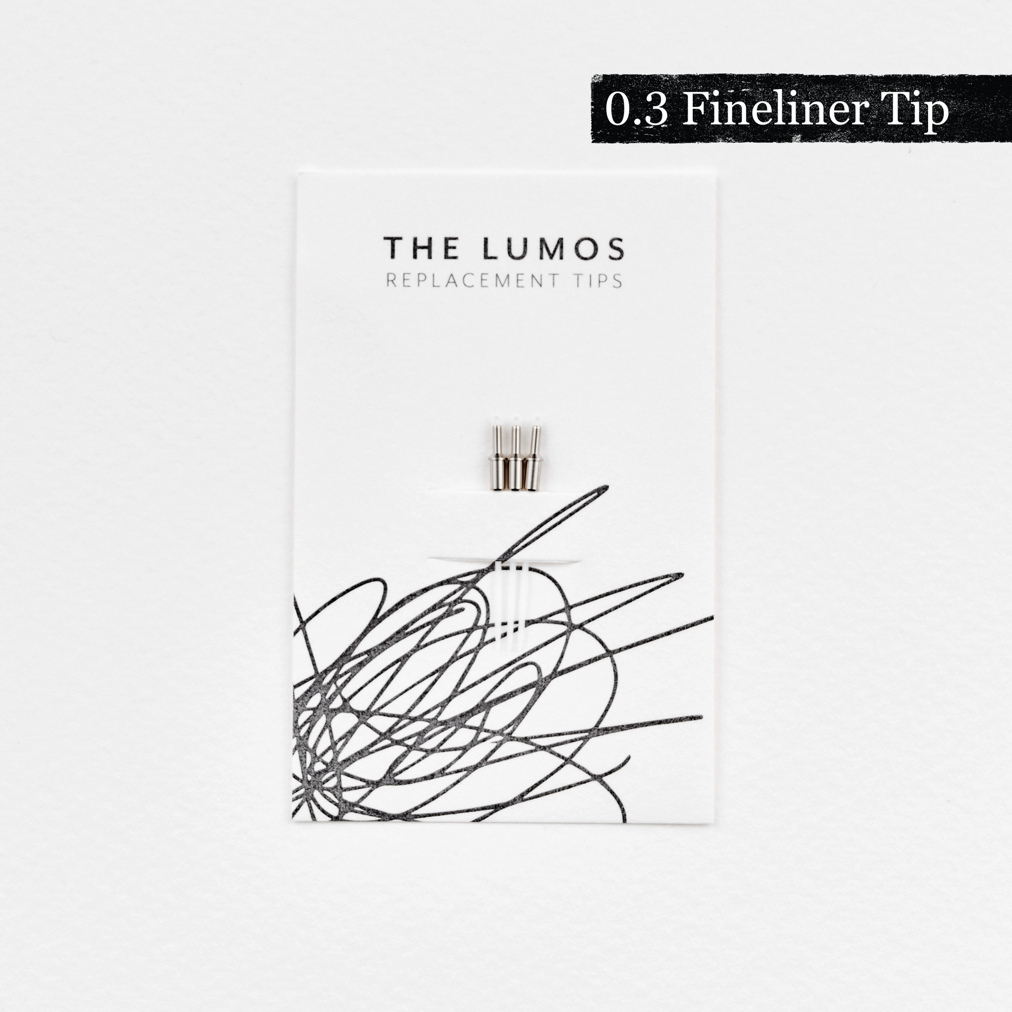 A pack of three Lumos 0.3mm fineliner replacement tips attached to a white backing card. The card features 'THE LUMOS REPLACEMENT TIPS' in uppercase black letters at the top, with an abstract black ink scribble design in the lower half. A black textured label in the upper right corner displays '0.3 Fineliner Tip' in white text. 