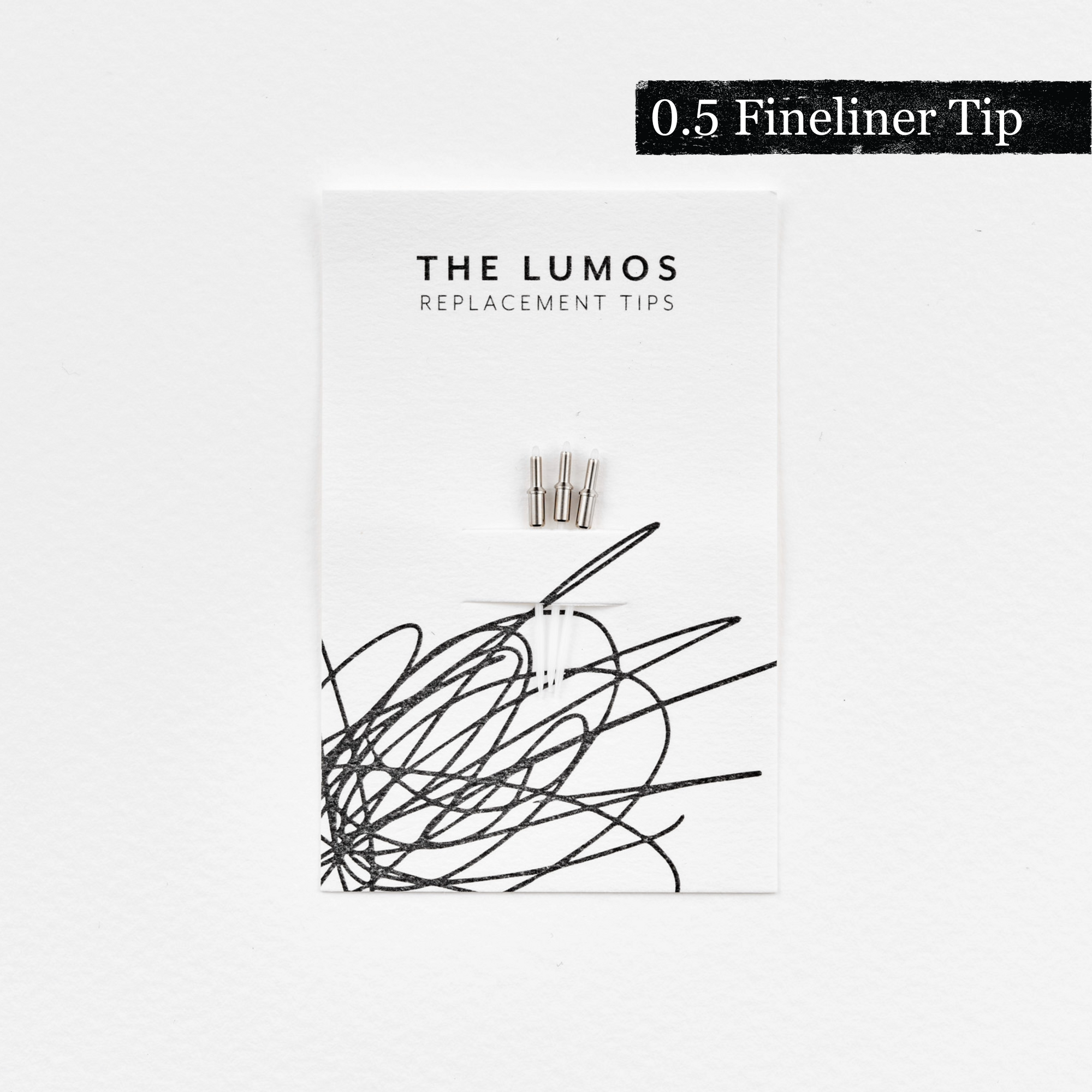 A pack of three Lumos 0.5mm fineliner replacement tips attached to a white backing card. The card features &#39;THE LUMOS REPLACEMENT TIPS&#39; in uppercase black letters at the top, with an abstract black ink scribble design in the lower half. A black textured label in the upper right corner displays &#39;0.5 Fineliner Tip&#39; in white text. 