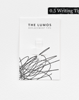 A pack of three Lumos replacement 0.5 Writing tips attached to a white backing card. The card features 'THE LUMOS REPLACEMENT TIPS' in uppercase black letters at the top, with an abstract black ink scribble design in the lower half. A black textured label in the upper right corner displays '0.5 Writing Tip' in white text. 