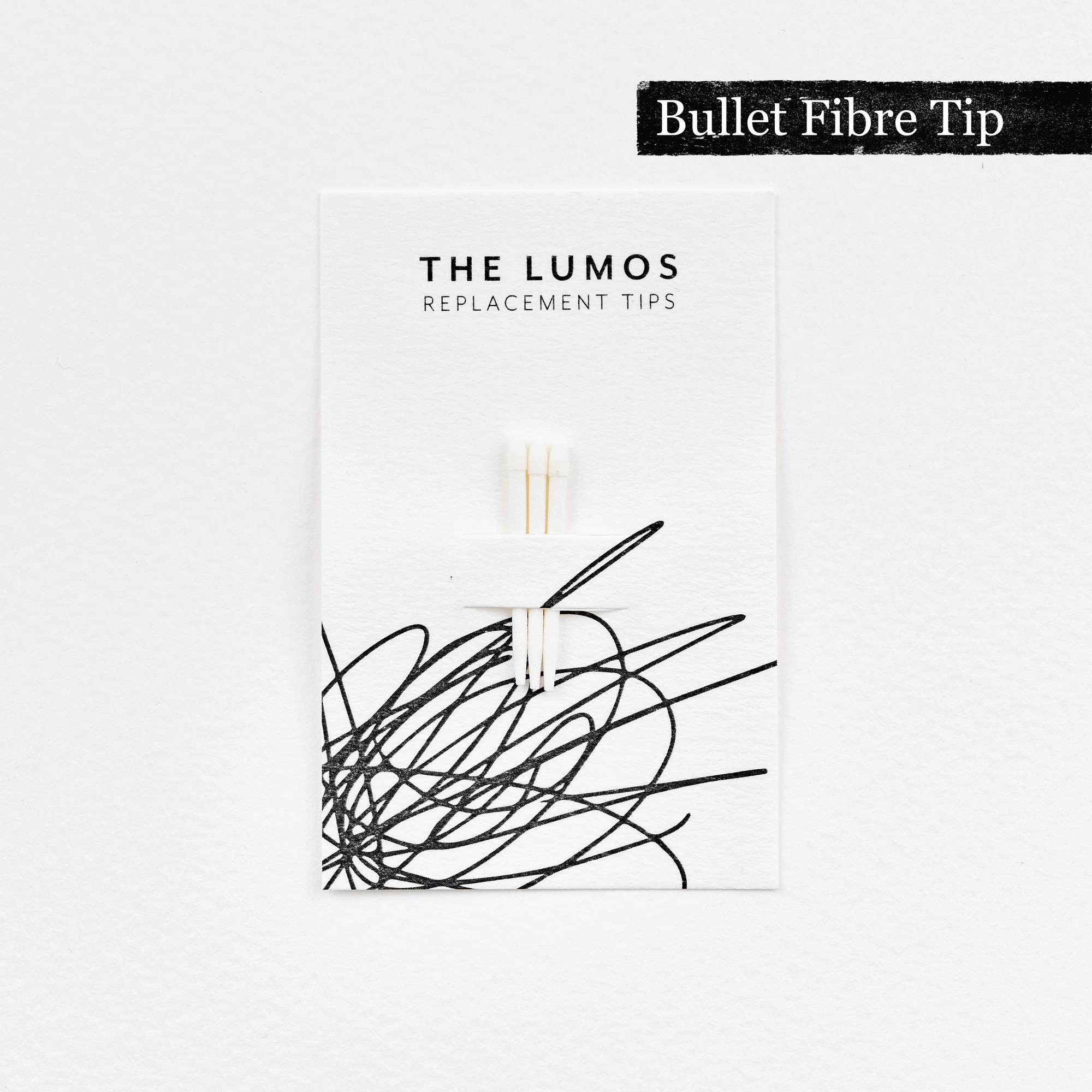 A pack of three Lumos replacement Bullet Fibre tips attached to a white backing card. The card features &#39;THE LUMOS REPLACEMENT TIPS&#39; in uppercase black letters at the top, with an abstract black ink scribble design in the lower half. A black textured label in the upper right corner displays &#39;Bullet Fibre Tip&#39; in white text. 