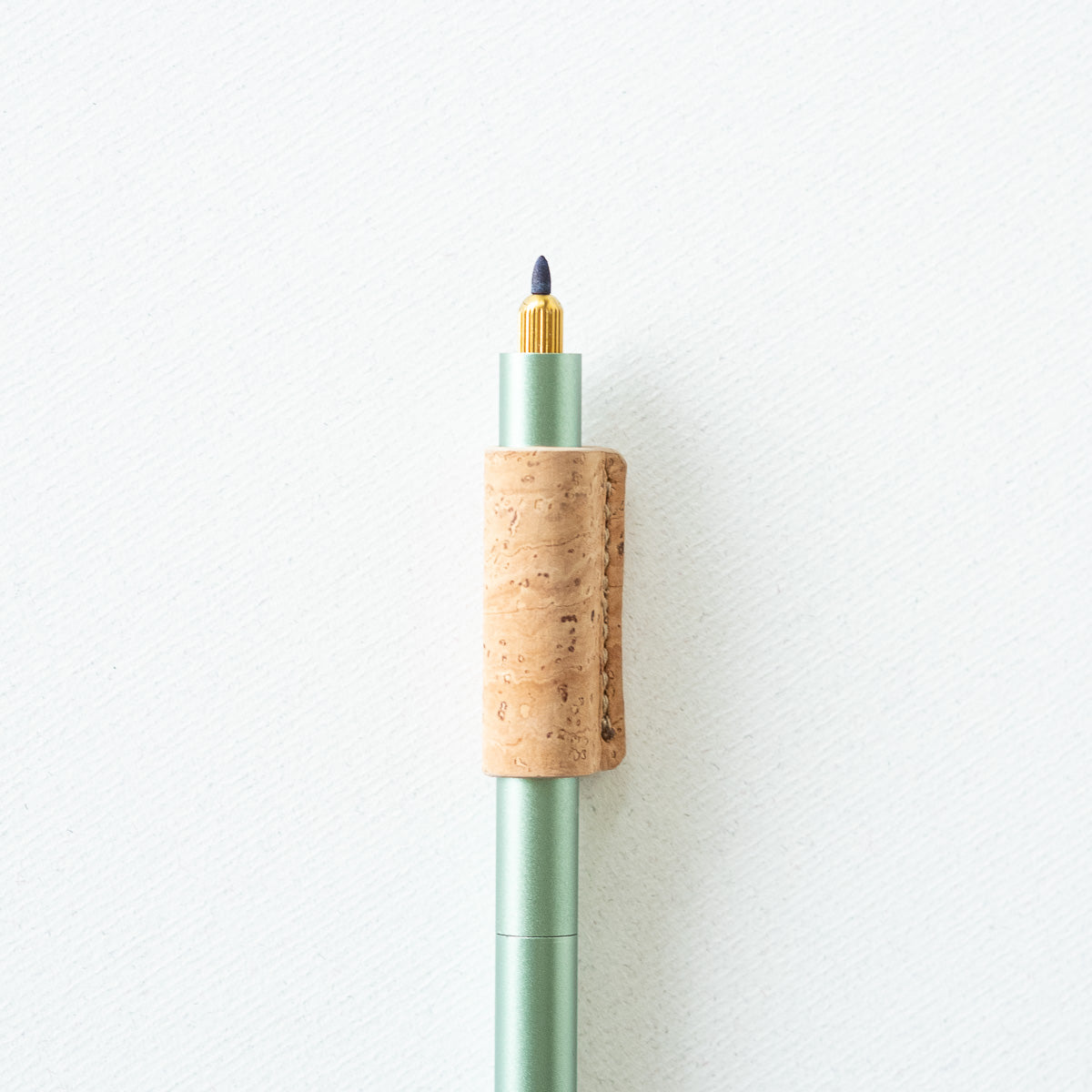 Handmade by Edward De Lacy, a pen grip and rollstop for the Lumos refillable pen – shown in cork on the sage Lumos