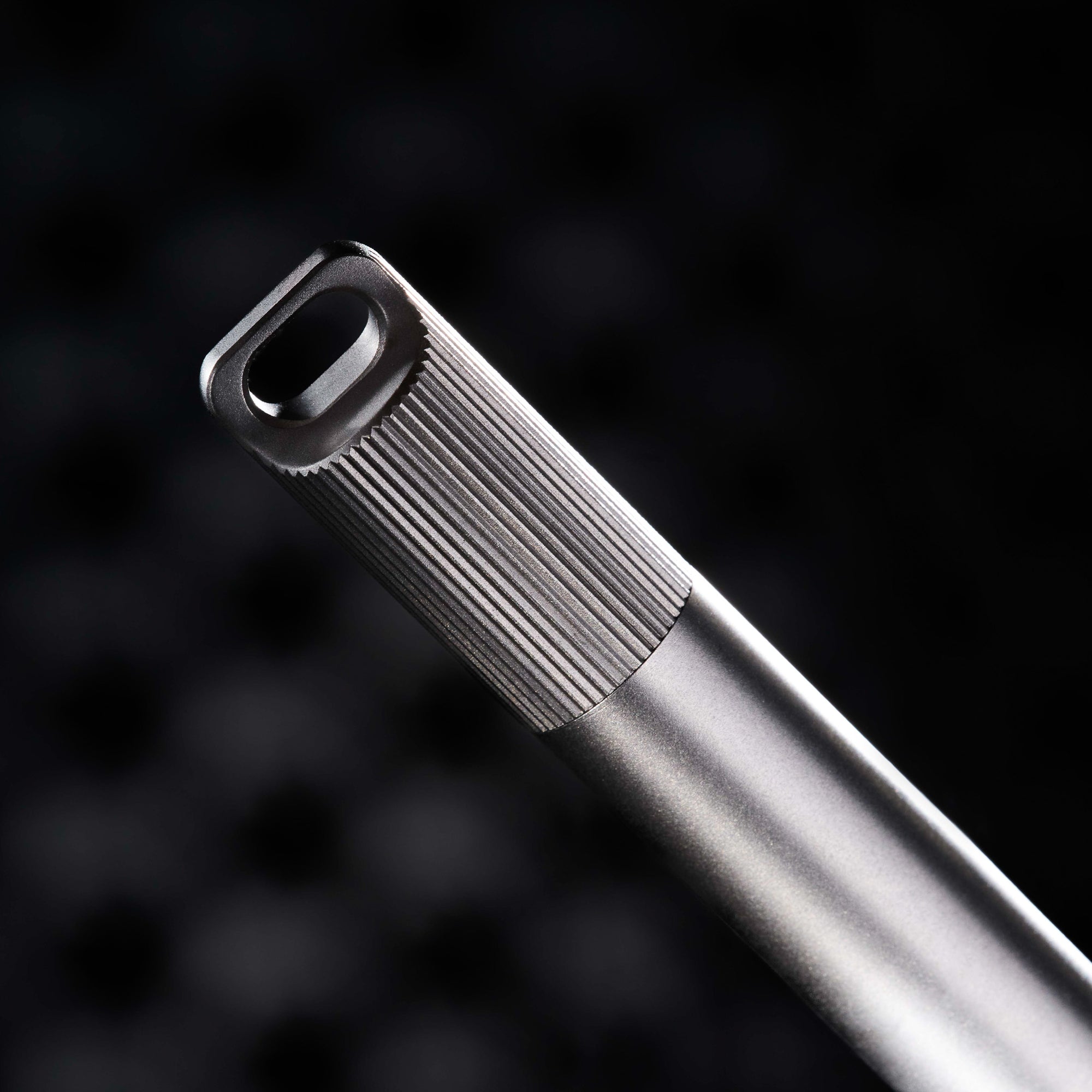 Detail shot of the Titanium Lumos loop lid, showcasing its grooved texture, bead-blasted finish, and signature oblong loop design.