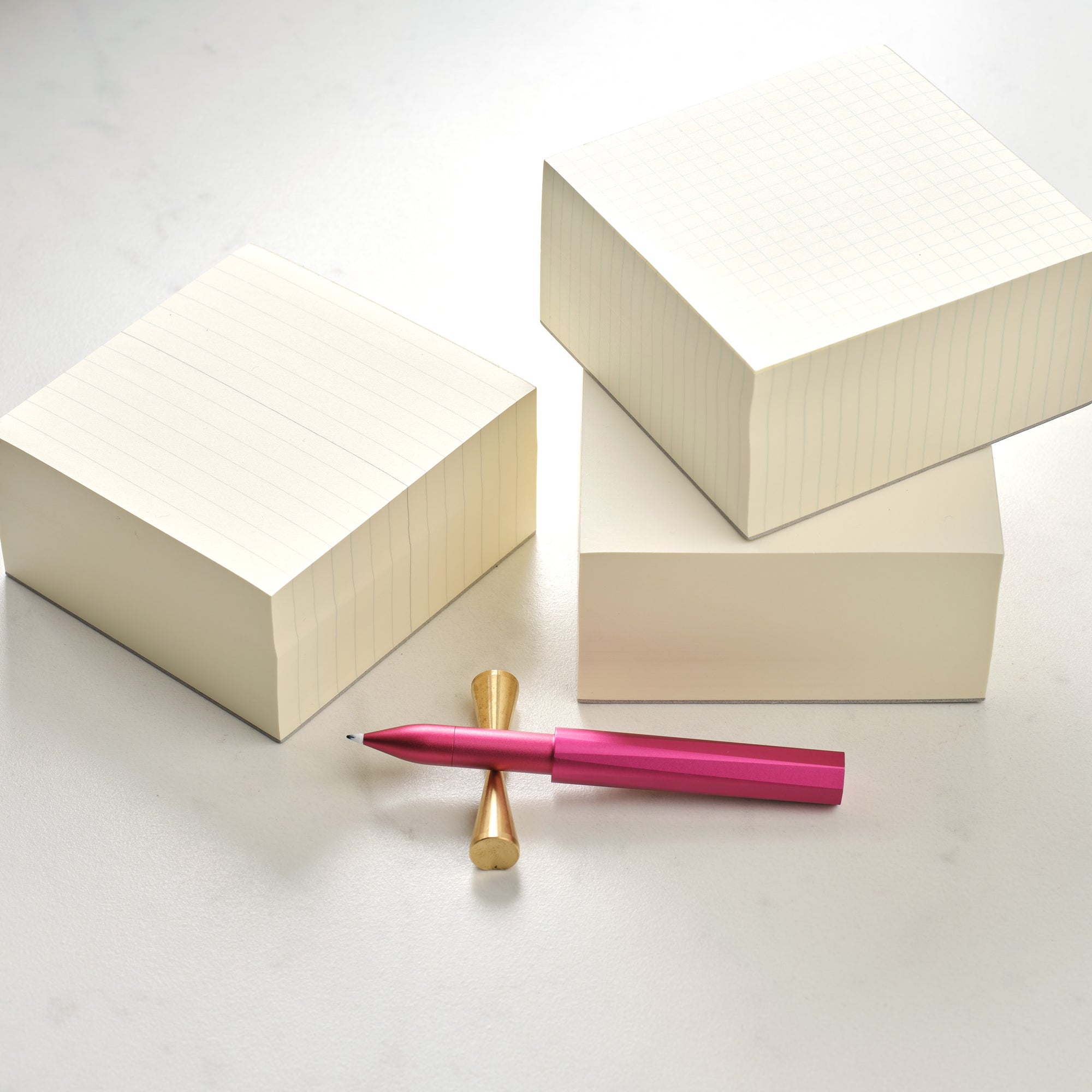 Three MD Memo Blocks – plain, ruled and grid, with the Wren refillable writing pen in Raspberry on a Brass Butterfly Pen Rest.