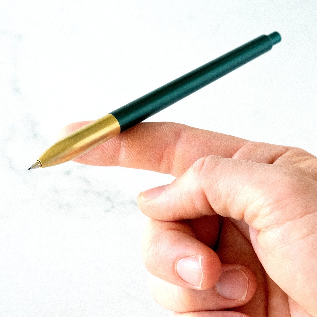 The Tom&#39;s Studio Mechanical Pencil in Ivy, balanced on an outstretched finger