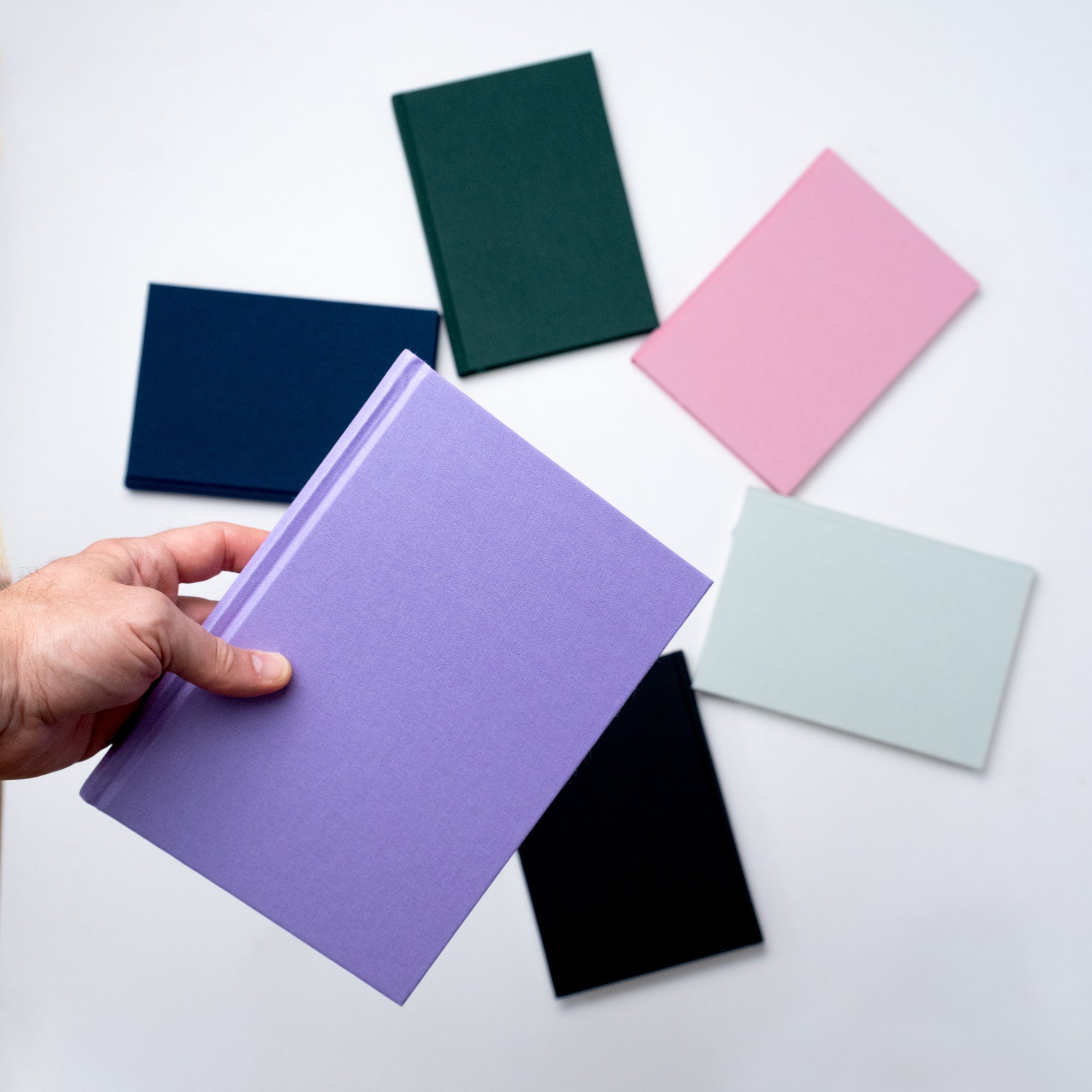 A collection of vibrant Semikolon A5 notebooks in various colours, with premium linen bound covers, in a spiral arrangement.