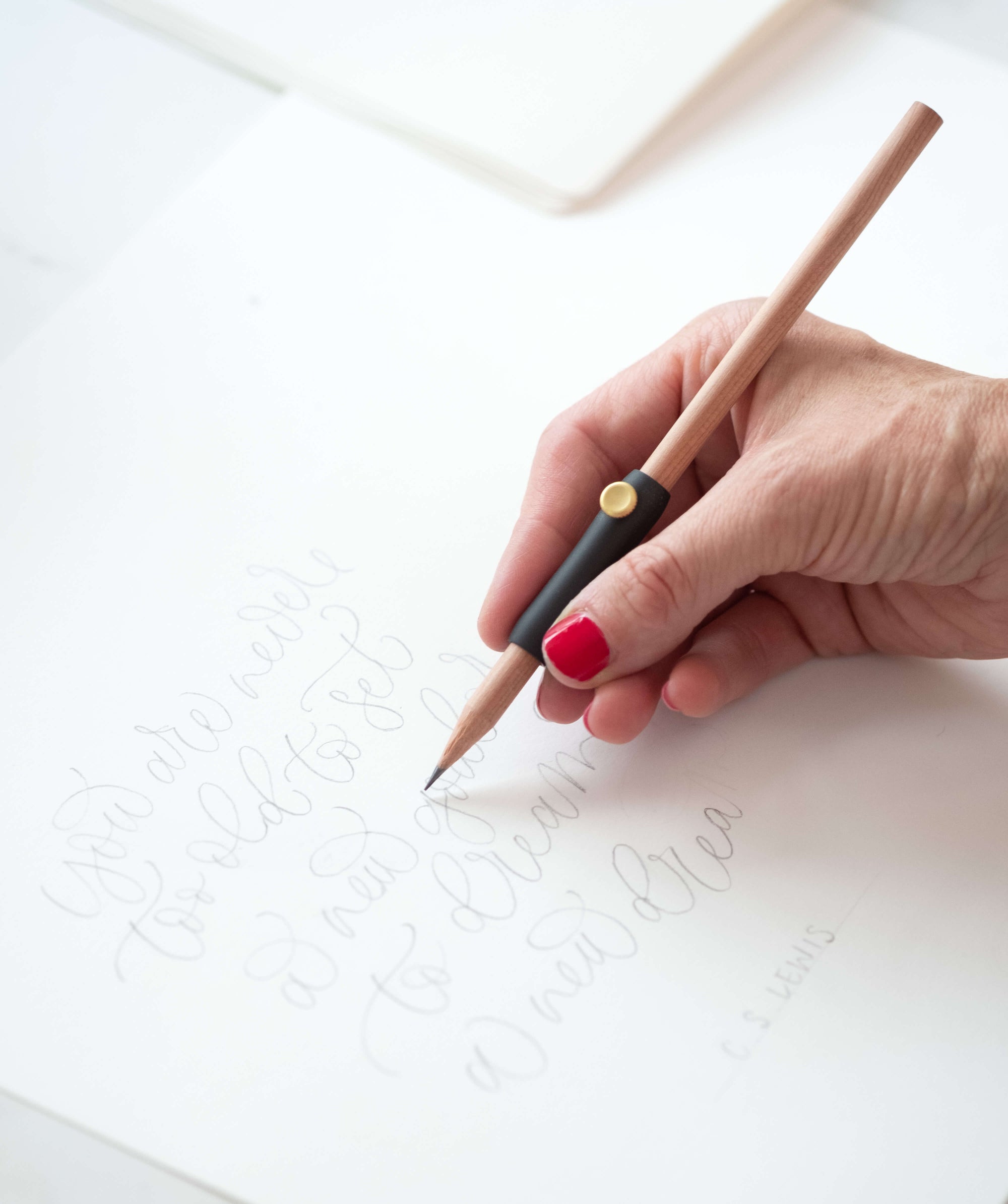 The Poise Pencil Grip Extender in Black. Shown in use preparing a calligraphy piece.