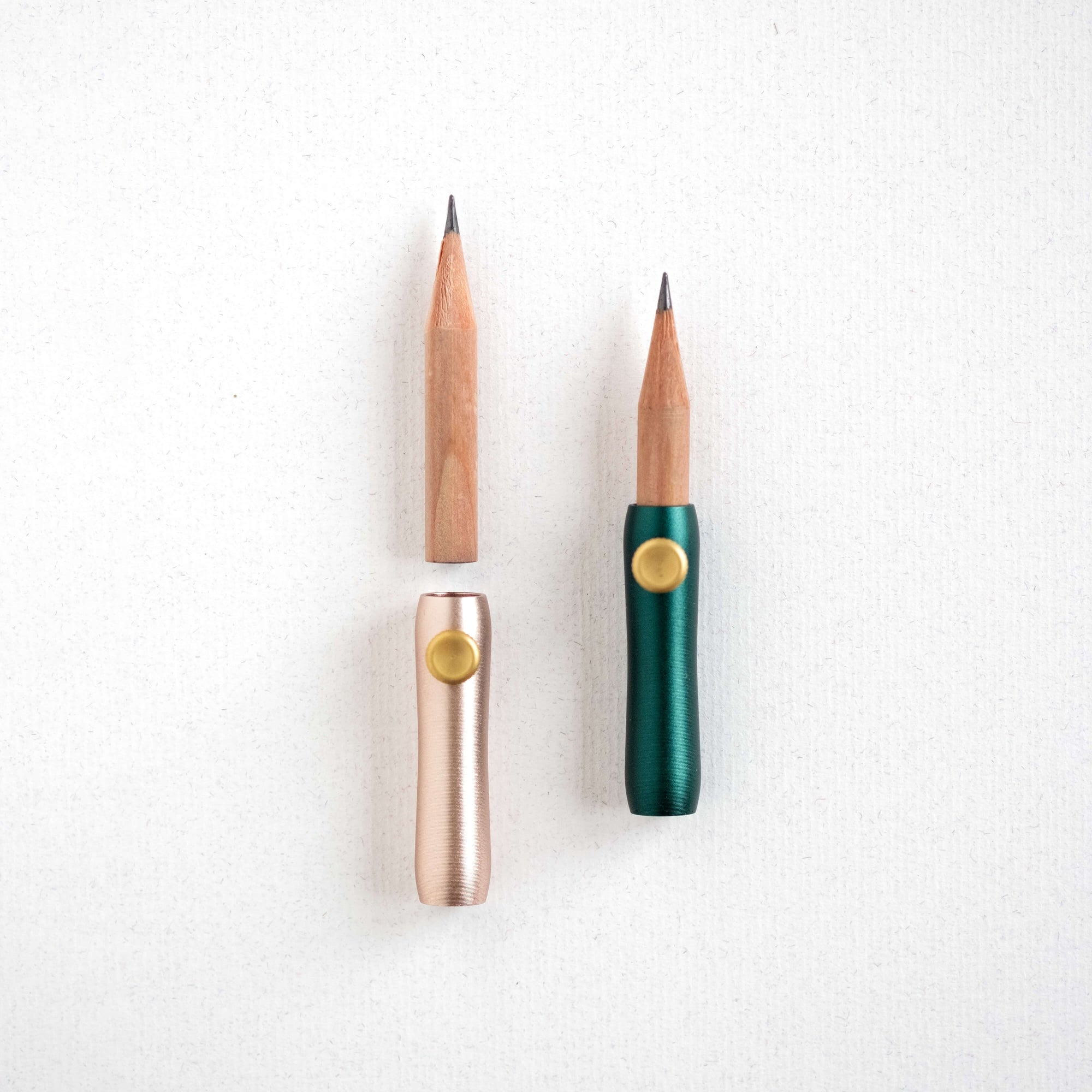 The Poise Pencil Grip Extender in (left to right) Blush and Ivy. Shown on a short pencil.