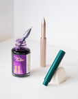 The Wren refillable everyday writing pen in (left to right) Lilac, Blush and Ivy with a bottle of Iris Fountain Pen Ink – showing how to fill the ink reservoir