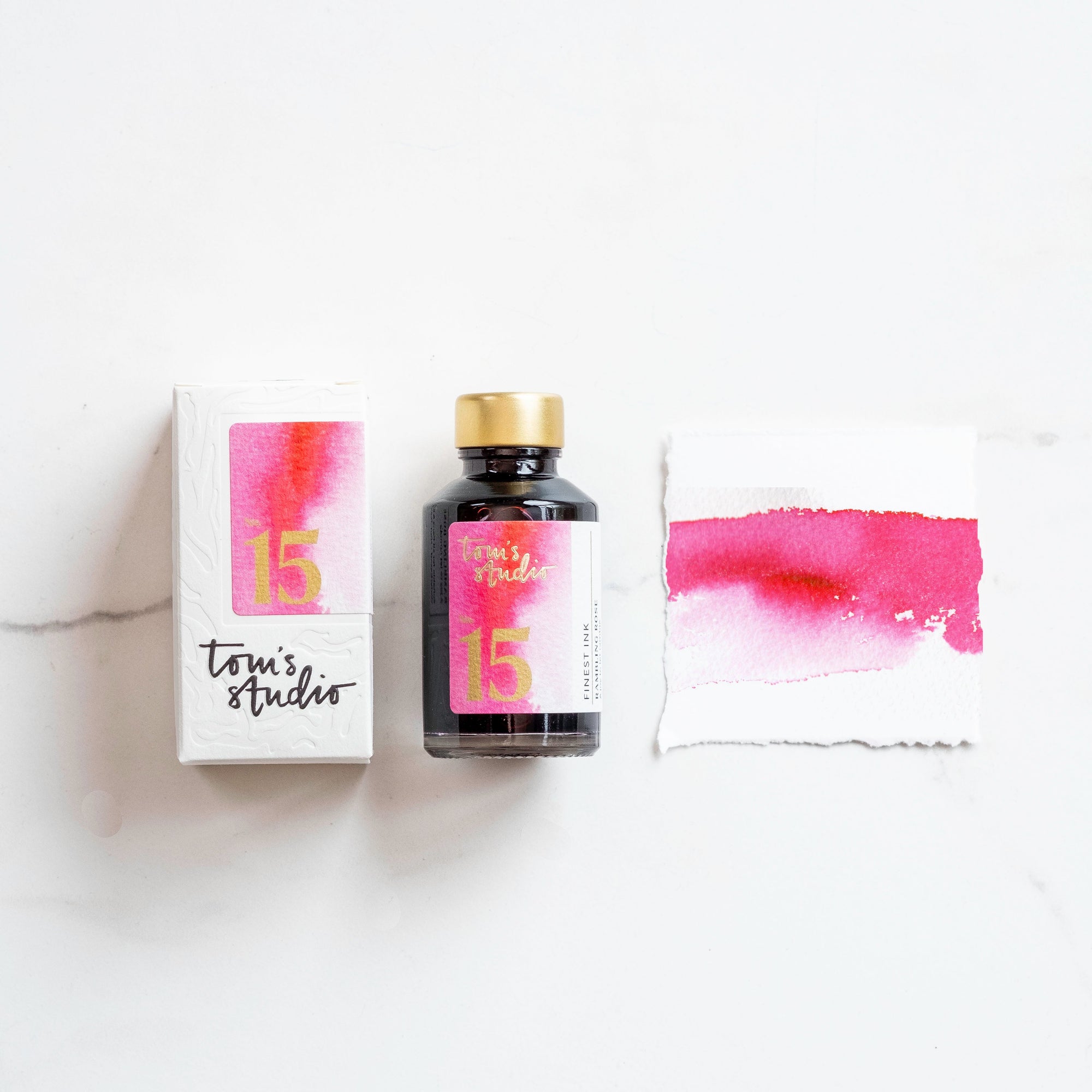 Tom's Studio Rambling Rose Fountain Pen Ink with two pens with inky goodness on paper with an ink swatch demonstrating the colour