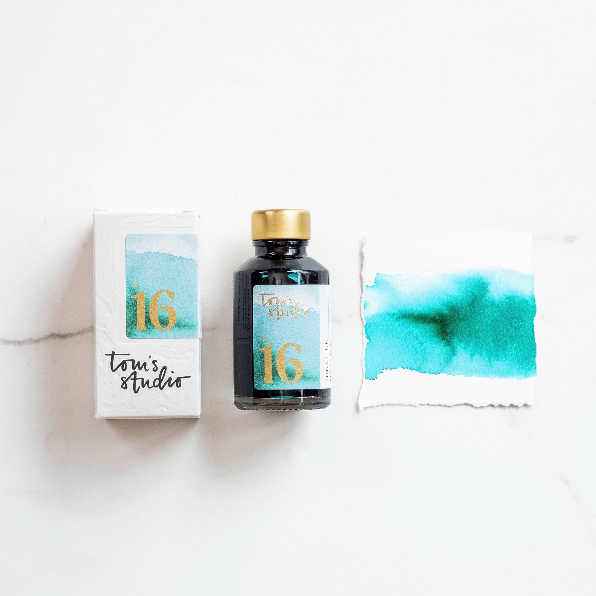 Tom's Studio Sunny Teal Fountain Pen Ink with two pens with inky goodness on paper with an ink swatch demonstrating the colour